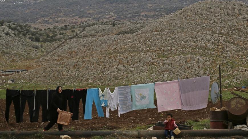 A Syrian woman carries a basket after hanging clothes to dry outside her tent in the Lebanese village of Kefraya in west Bekaa March 2, 2015. REUTERS/Jamal Saidi (LEBANON - Tags: SOCIETY IMMIGRATION) - RTR4RSW6