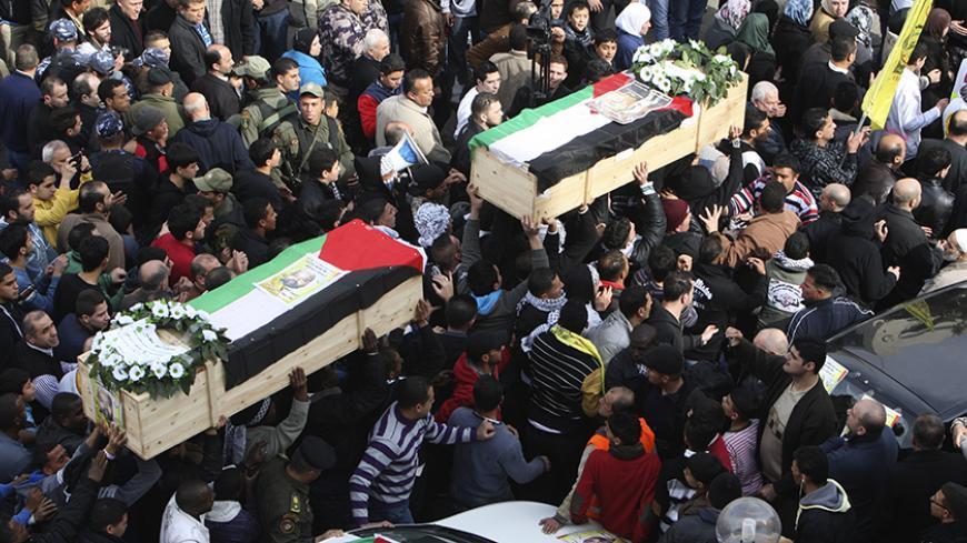 Palestinians carry coffins containing the remains of Palestinian militants Fathi Ameereh (R) and Ata Samahneh during their funeral in the West Bank city of Nablus January 22, 2014. Israel begun to exhume the remains of a number of Palestinian militants, including Ameereh and Samahneh, to return them to their families for burial, the army said on Sunday, a move that could help ease some tension between the adversaries.  REUTERS/Abed Omar Qusini (WEST BANK - Tags: POLITICS CIVIL UNREST OBITUARY) - RTX17PKK