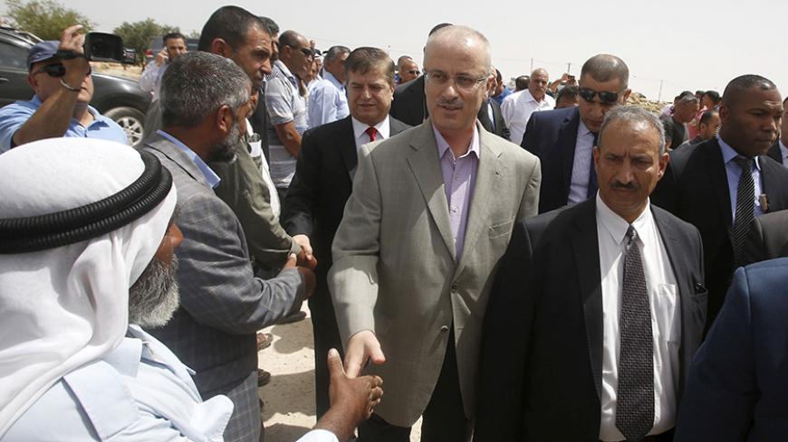 A Palestinian man shakes hands with Palestinian Prime Minister Rami Hamdallah (C) during Hamdallah's visit to Susya village, south of the West Bank city of Hebron June 8, 2015. Residents of Susya village, living in tents erected on the top of sand hills for almost 30 years, feared that Israel would drive them out of the area. The village is located in an area classified in Israeli-Palestinian peace accords as Area C, where Palestinian residents must obtain a license to build or stay there. REUTERS/Mussa Qaw