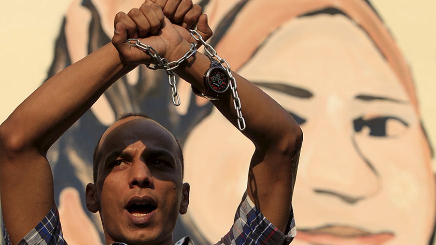 A protester holds up his hands, which are chained together, as journalists and members of the April 6 movement protest against the restriction of press freedom and demand the release of detained journalists in front of the Press Syndicate in Cairo June 10, 2015. Egyptian security forces have arrested dozens of activists ahead of a general strike planned for Thursday, activists and security sources say, part of what the activists describe as an unrelenting crackdown on dissent. REUTERS/Mohamed Abd El Ghany -