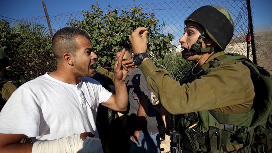 A Palestinian argues with an Israeli soldier during confrontations in Qafr Malik village near the West Bank city of Ramallah June 14, 2015. An Israeli army jeep struck and killed a Palestinian in the occupied West Bank on Sunday, with the military and locals giving conflicting accounts of the circumstances. A military spokeswoman said the jeep, which was in Qafr Malik village as part of an operation to arrest suspected militants, accidentally hit the Palestinian after he threw a petrol bomb at it. Local res