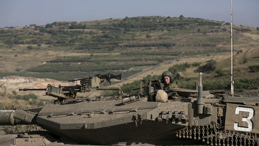 An Israeli soldier rides a tank on the Israeli side of the border fence between Syria and the Israeli-occupied Golan Heights, near Majdal Shams, June 16, 2015. Israel's president expressed his concern to the United States last week about the fate of the Druze minority in Syria, saying around 500,000 of them were under threat from Islamist militants in an area near the Israeli border. REUTERS/Baz Ratner  - RTX1GRYM