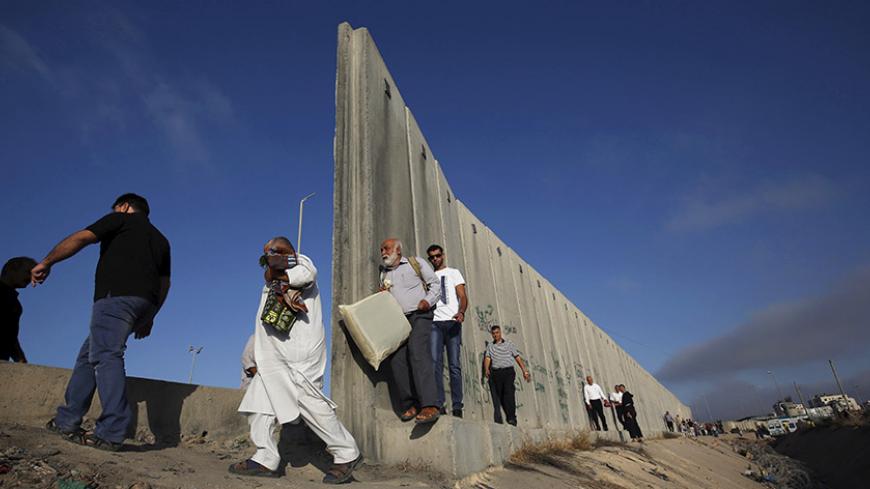 Palestinians walk past Israel's controversial barrier as they make their way to attend the third Friday prayer of Ramadan in Jerusalem's al-Aqsa mosque, through Qalandia checkpoint near the West Bank city of Ramallah July 3, 2015. REUTERS/Mohamad Torokman 
 - RTX1IUJK