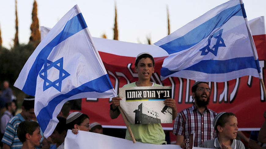 An Israeli protester holds a placard and a flag during a demonstration against a court decision to demolish housing units in the Jewish settlement of Beit El, outside the Supreme Court in Jerusalem July 8, 2015. Israel's Supreme Court ruled that 24 housing units, built on Palestinian owned land, be razed by July 30, according to local media. The placard in Hebrew reads, "The Supreme Court is ruining us". REUTERS/Ammar Awad - RTX1JMGQ