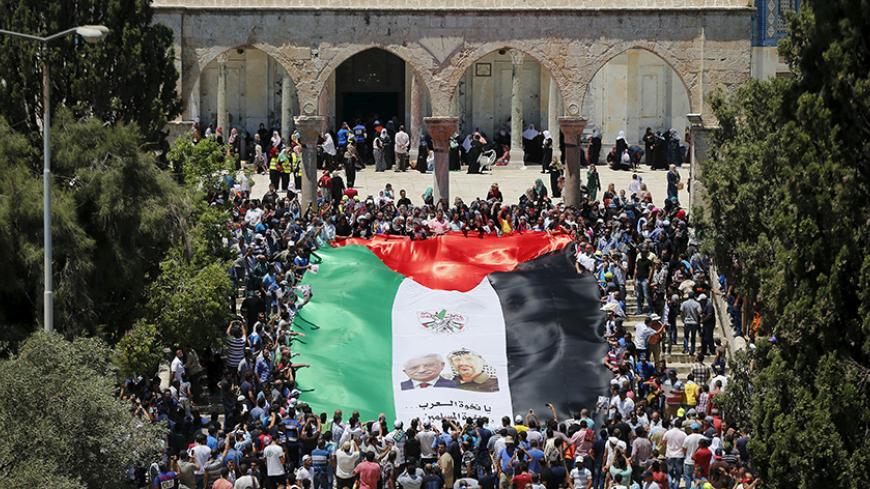 Palestinians hold a large flag depicting President Mahmoud Abbas (L) and late Palestinian leader Yasser Arafat during a rally marking the annual al-Quds Day, or Jerusalem Day, on the fourth Friday of the holy month of Ramadan, at the compound known to Muslims as the Noble Sanctuary and to Jews as Temple Mount, in Jerusalem's Old City July 10, 2015. An Israeli police spokesperson said on Friday that some 140,000 people attended the prayers on the compound and some 56,000 Palestinians from the West Bank enter