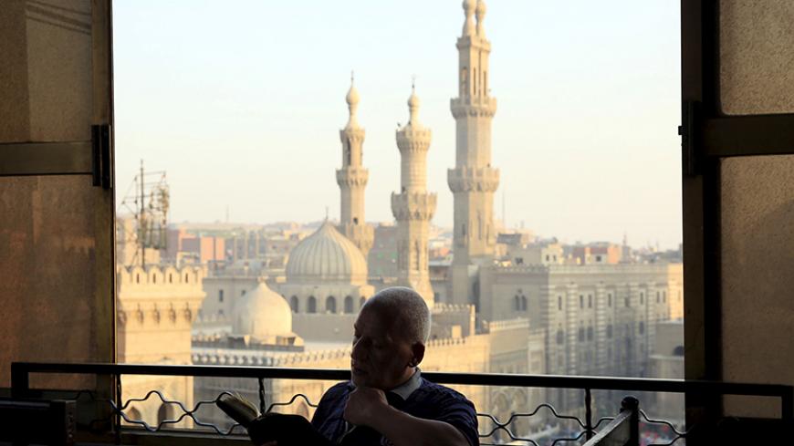 A man reads the Koran minutes before sunset as he waits to break his fast and have his Iftar meal near Al-Azhar mosque, in the old Islamic area of Cairo, Egypt, July 9, 2015. Picture taken July 9, 2015. REUTERS/Amr Abdallah Dalsh - RTX1JWC3