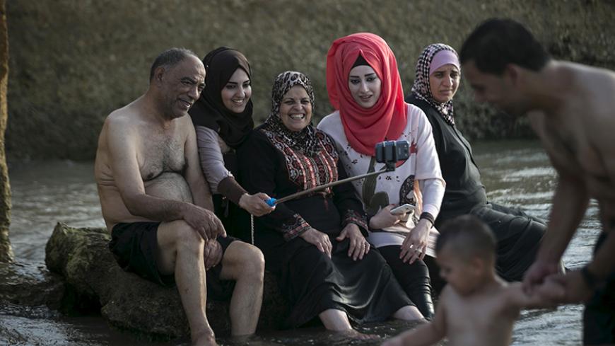 A Palestinian family takes a selfie on a beach of the Mediterranean in Tel Aviv during Eid al-Fitr, which marks the end of the holy month of Ramadan July 19, 2015. Thousands of Palestinians used permits given by the Israeli authorities allowing many to enjoy the beaches along Israel's Mediterranean shoreline during the Eid al-Fitr holiday. REUTERS/Baz Ratner      TPX IMAGES OF THE DAY      - RTX1KXU4