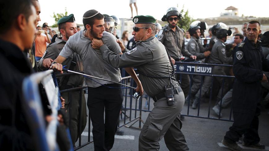A Jewish settler (2nd L) scuffles with an Israeli border police officer near buildings slated for demolition by order of Israel's high court, in the West Bank Jewish settlement of Beit El, near Ramallah July 28, 2015. Israeli police said on Tuesday that forces were deployed to the settlement in the occupied West Bank in order to prevent people from barricading themselves inside the structures known as the "Drainhoff" buildings. REUTERS/Amir Cohen      TPX IMAGES OF THE DAY      - RTX1M69K