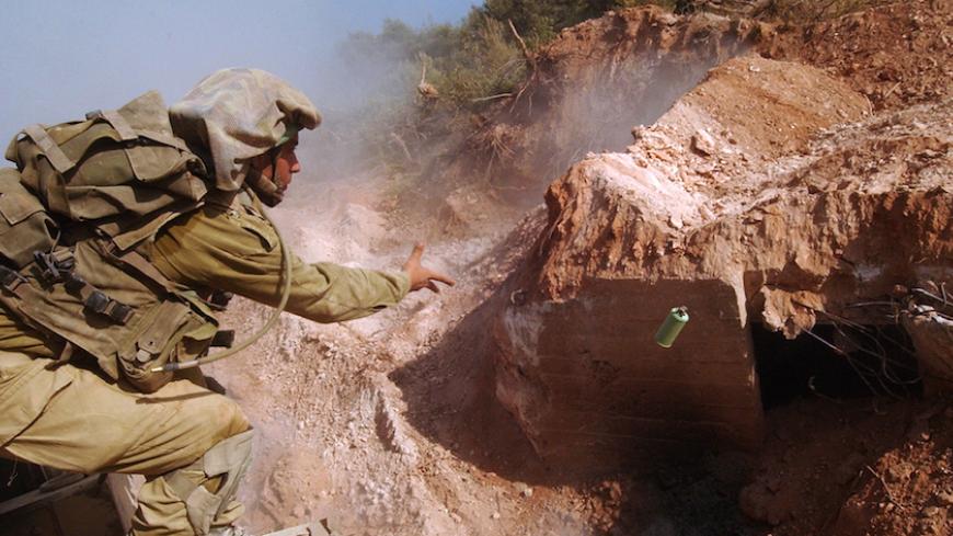 An Israeli soldier throws a gas grenade towards a Hizbollah bunker that was uncovered in southern Lebanon August 27, 2006, in this picture released by the Israeli Defense Forces August 28, 2006. Israeli special forces have been exploiting the end of fighting with Hizbollah to uncover and destroy the guerrilla group's tunnel and bunker networks in southern Lebanon, military officials said on Monday.  Picture taken August 27, 2006.  FOR EDITORIAL USE ONLY   REUTERS/IDF/Handout (LEBANON) - RTR1GRL7