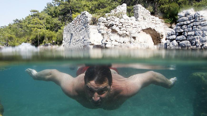 A tourist swims around the flooded ruins of an ancient Roman Bath in a small bay called Hamam Koy near Gocek Bay in Mugla province June 13, 2012. REUTERS/Umit Bektas (TURKEY - Tags: ENVIRONMENT SOCIETY TRAVEL) - RTR33JXH