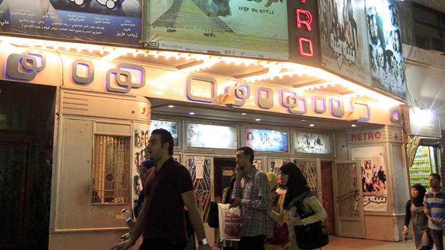 People walk past a poster of the movie "After the Battle" outside a cinema in Cairo October 16, 2012. When horse and camel riders attacked protesters in Cairo's Tahrir Square during last year's uprising, Egyptian filmmaker Yousry Nasrallah was struck by one of the most vivid examples of how Egypt's huge class divide is exploited by powerful elites. Nasrallah's "After the Battle" tells the story of how one of the horsemen struggles to come to terms with his role in the aftermath of one of the most violent in