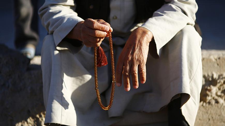 A Kurdish refugee man from the Syrian town of Kobani holds prayer beads in a camp in the southeastern town of Suruc, Sanliurfa province October 24, 2014. REUTERS/Kai Pfaffenbach (TURKEY - Tags: MILITARY CONFLICT POLITICS RELIGION) - RTR4BEW0