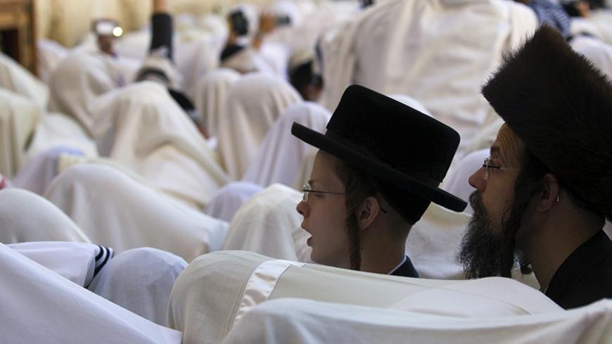 An ultra-Orthodox Jewish boy stands among worshippers covered with prayer shawls during a special priestly blessing for Passover at the Western Wall, Judaism's holiest prayer site, in Jerusalem's Old City April 6, 2015. REUTERS/Ronen Zvulun  - RTR4W8AK