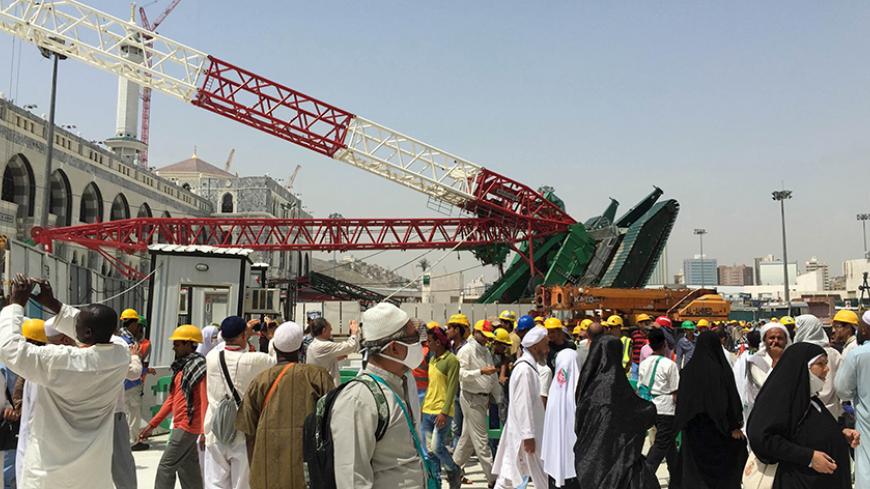 Muslim pilgrims walk near a construction crane which crashed in the Grand Mosque in the Muslim holy city of Mecca, Saudi Arabia September 12, 2015. At least 107 people were killed when the crane toppled over at Mecca's Grand Mosque on Friday, Saudi Arabia's Civil Defence authority said, less than two weeks before Islam's annual haj pilgrimage. REUTERS/Mohamed Al Hwaity - RTSR3D