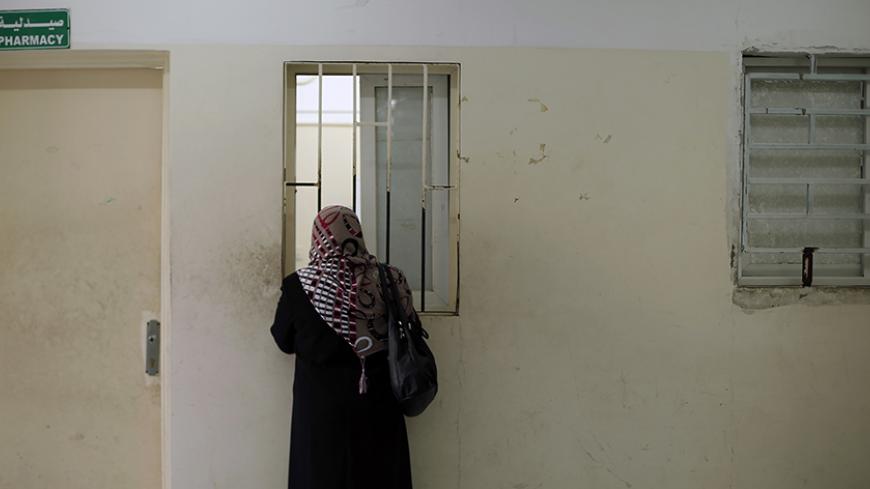 A Palestinian woman waits to receive medicine from a pharmacy at a hospital in Gaza City December 10, 2013. REUTERS/Suhaib Salem (GAZA - Tags: HEALTH) - RTX16CAD