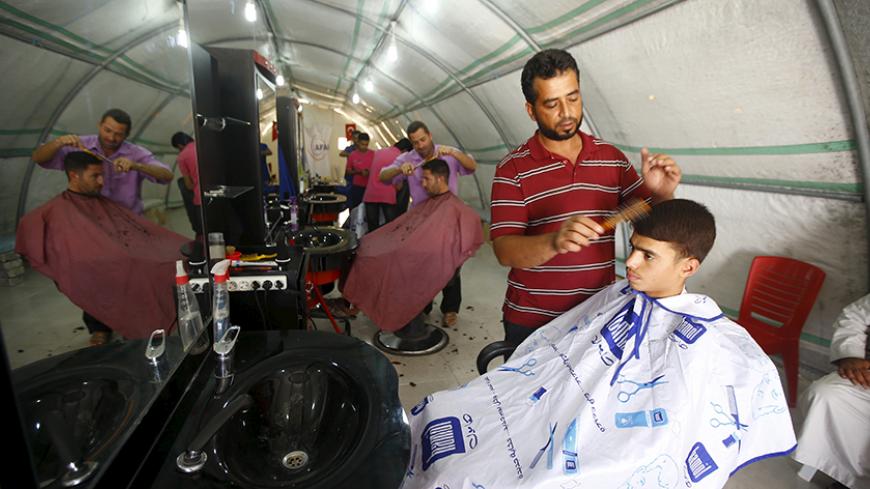 A hairdresser cuts the hair of a customer at Suleymansah refugee camp in Akcakale in Sanliurfa province, Turkey, June 11, 2015. REUTERS/Osman Orsal

 - RTX1G4C9