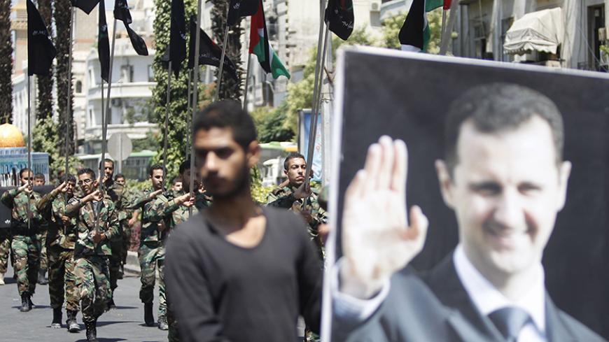 Palestinians living in Syria carry flags as one of them holds a picture depicting Syria's President Bashar al-Assad during a rally marking the annual al-Quds Day, or Jerusalem Day, on the last Friday of the Muslim holy month of Ramadan in Damascus, Syria July 10, 2015. REUTERS/Omar Sanadiki - RTX1JVFC