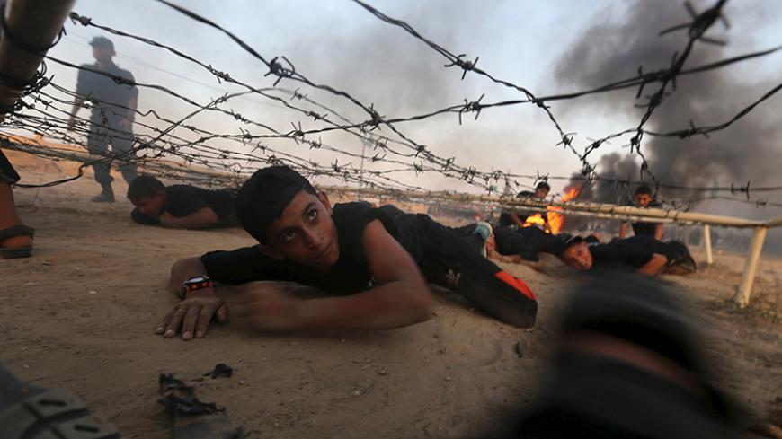 Young Palestinians crawl under an obstacle during a military-style exercise at Liberation Youths summer camp, organised by the Hamas movement, in Rafah in the southern Gaza Strip, August 1, 2015. Hamas stages dozens of military-style summer camps for young Palestinians in the Gaza Strip to prepare them to "confront any possible Israeli attack", organisers said.  REUTERS/Ibraheem Abu Mustafa      TPX IMAGES OF THE DAY      - RTX1MOQN
