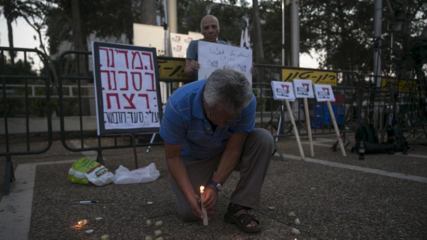 A man lights a candle in memory of 18-month-old Palestinian boy Ali Dawabsheh during a protest condemning Friday's arson attack in the West Bank, at Rabin square in Tel Aviv August 1, 2015. Some 3,000 demonstrators gathered for the rally organised by the Israeli anti-settler group Peace Now against the attack by suspected Jewish assailants who torched a Palestinian home in the occupied West Bank on Friday, killing an 18-month-old toddler and seriously injuring three other family members, an act that Israel'