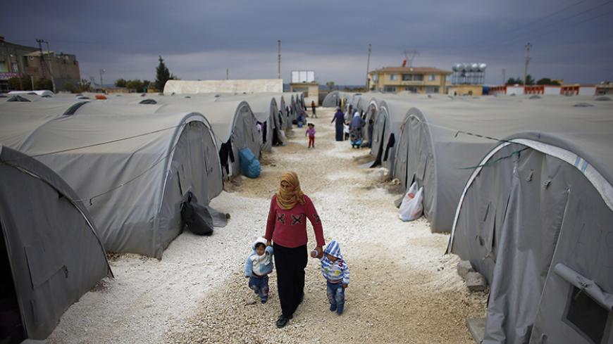 A Kurdish refugee woman from the Syrian town of Kobani walks with her children at a refugee camp in the border town of Suruc, Sanliurfa province November 17, 2014. REUTERS/Osman Orsal (TURKEY - Tags: POLITICS CONFLICT) - RTR4EES6