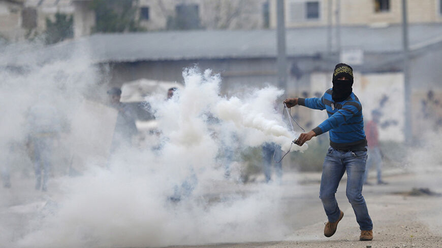 A Palestinian protester uses a sling to return a tear gas canister fired by Israeli troops during clashes near Israel's Ofer Prison, near the West Bank city of Ramallah, April 10, 2015. Israeli troops killed a Palestinian stone-thrower and wounded several others in the occupied West Bank on Friday after a militant's funeral turned violent, hospital officials and witnesses said. An army spokeswoman confirmed soldiers opened fire during the incident at Beit Omar, near the Palestinian city of Hebron, saying th