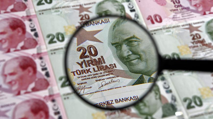 A 20 lira banknote is seen through a magnifying lens in this illustration picture taken in Istanbul January 28, 2014. Turkey's central bank governor raises hopes of emergency rate hike in face of opposition from Prime Minister Tayyip Erdogan, denying he is hostage to political pressures and vowing to fight rising inflation and tumbling lira. REUTERS/Murad Sezer (TURKEY  - Tags: BUSINESS POLITICS) - RTX17YSG