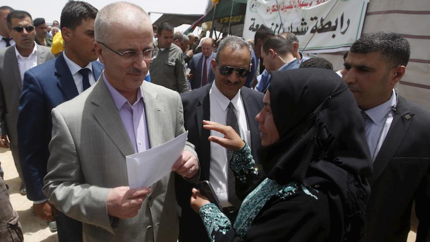 A Palestinian woman talks to Palestinian Prime Minister Rami Hamdallah (L) during his visit to Susya village south of the West Bank city of Hebron June 8, 2015. Residents of Susya village, living in tents erected on the top of sand hills for almost 30 years, feared that Israel would drive them out of the area. The village is located in an area classified in Israeli-Palestinian peace accords as Area C, where Palestinian residents must obtain a license to build or stay there. REUTERS/Mussa Qawasma - RTX1FMLZ