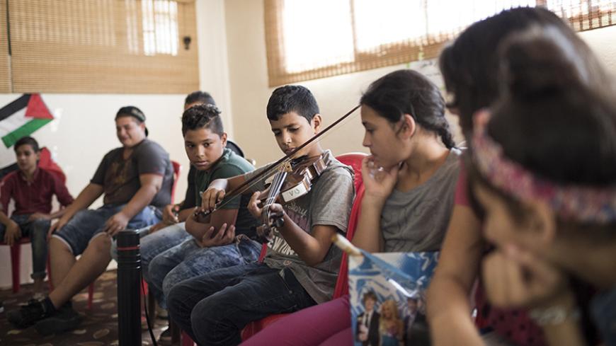 Beirut, Lebanon, October 11, 2015 - Students attend a music lesson organised by the Al Kamandjati association in the Palestinian refugee camp of Shatila. 

Al Kamandjati, which means "The Violinist" in Arabic, was founded in 2002 by Palestinian violist Ramzi Aburedwan, who is from the Al Amari refugee camp in Ramallah. The association aims to make music accessible to Palestinian children, particularly those living in refugee camps and villages in Palestine and Lebanon.