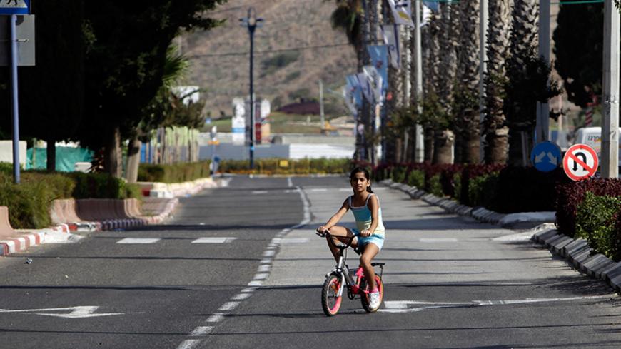 A girl rides her bike on an empty street during the Jewish holiday of Yom Kippur in the northern Israeli city of Acre October 8, 2011. Yom Kippur, or Day of Atonement, is the holiest of Jewish holidays, when observant Jews atone for the sins of the past year. REUTERS/Ammar Awad (ISRAEL - Tags: RELIGION SOCIETY) - RTR2SEJU