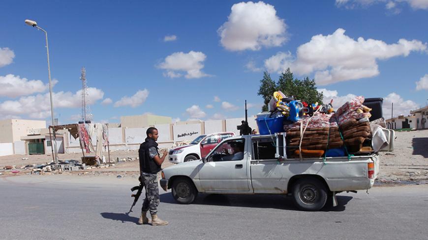 Civilians returning to their homes with their belongings pass a checkpoint manned by police in the centre of Bani Walid, some 170km (106 miles) south of Tripoli, November 3, 2012. REUTERS/Ismail Zitouny (LIBYA - Tags: POLITICS CIVIL UNREST) - RTR39Y9U