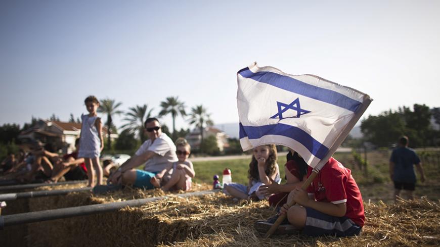 Children sit on bales of hay at the annual harvest festival in Kibbutz Degania Alef on the shores of the Sea of Galilee, northern Israel May 23, 2015. Twenty-five years ago kibbutzim, collective communities traditionally based on agriculture, seemed all but doomed. But the last few years have seen a surprising turnaround, with young families seeking to escape the high cost of living and alienation they find in cities for a cheaper, rural lifestyle in a closely knit community. Picture taken May 23, 2015. REU