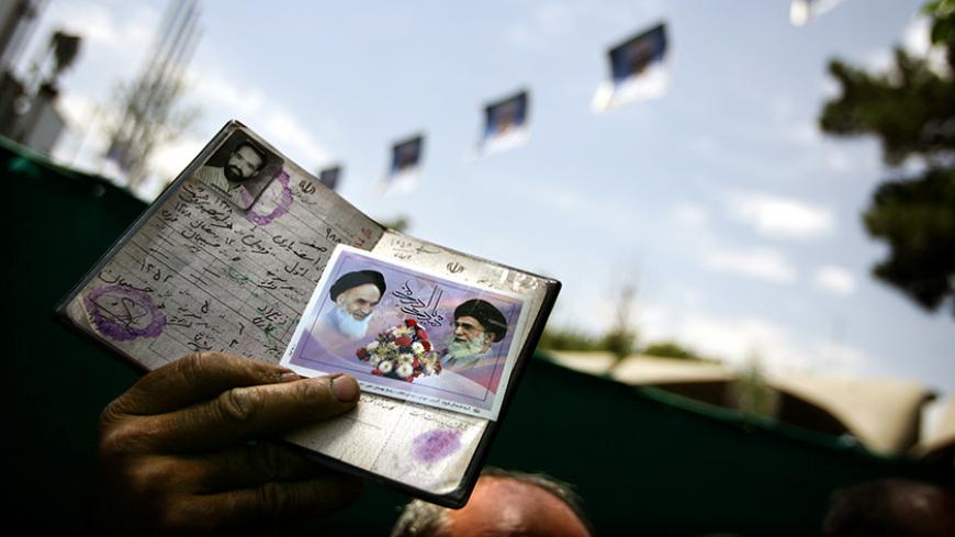 An Iranian man holds his passport as he waits to vote for the Iranian presidential election outside Tehran's university.  An Iranian man holds his passport, with pictures of the late founder of the Islamic Revolution Ayatollah Ruhollah Khomeini and Iran's supreme leader Ayatollah Ali Khamenei, as he waits to vote for the Iranian presidential election outside Tehran's university June 17, 2005. A top Iranian official said on Friday the election of a new president would have little impact on Iran's nuclear pol