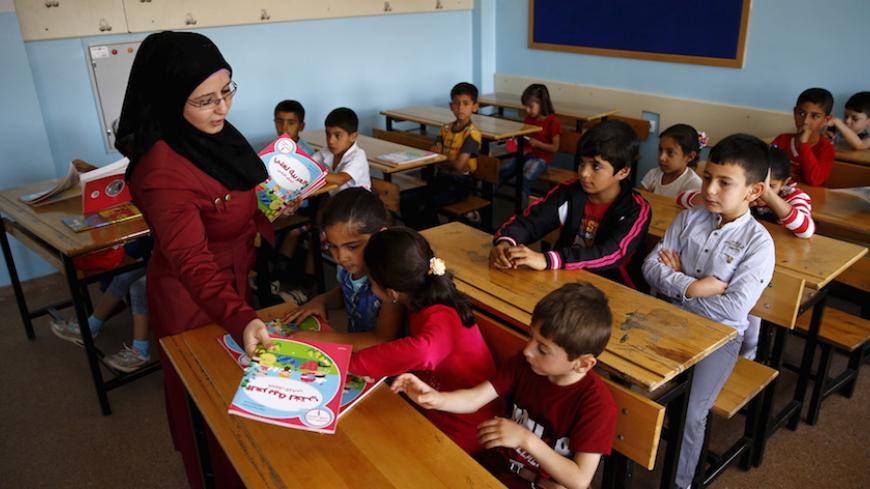 A Syrian refugee teacher distributes books to her refugee students in their classroom at Fatih Sultan Mehmet School in Karapurcek district of Ankara, Turkey, September 28, 2015. Out of 640,000 Syrian children in Turkey, 400,000 are not at school, a Turkish official told Reuters on Friday, warning that those who miss out are likely to be exploited by "gangs and criminals". Educating the children among more than 2.2 million Syrian refugees in Turkey - most of whom live outside purpose-built camps - is seen as