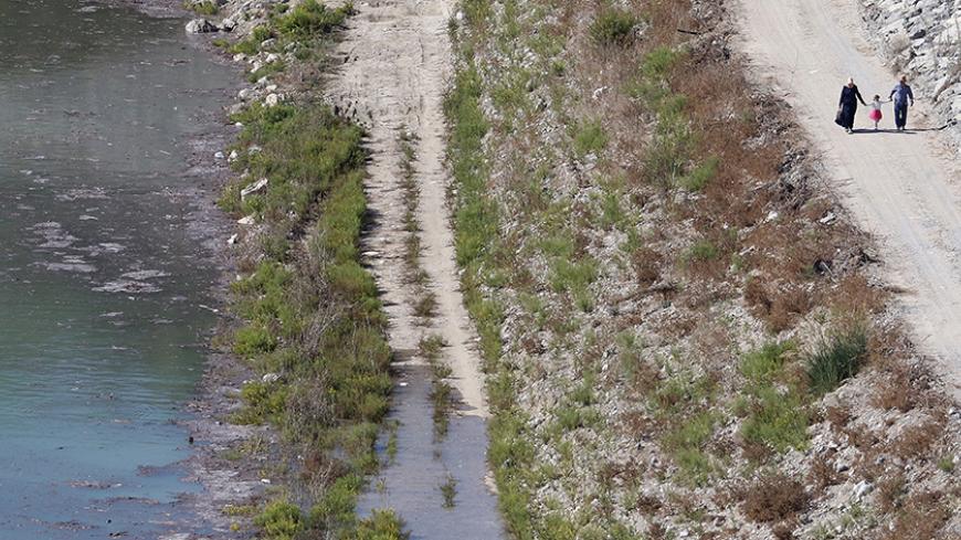 A family takes a stroll next to a reservoir in Myrtoy that will receive fresh water from Turkey via a water pipeline project linking Turkey to northern Cyprus Oct 17 2015. The 106-kilometre (66-mile) pipeline will transport some 75 million cubic metres (2.6 billion cubic feet) of water annually to northern Cyprus, a breakaway Turkish Cypriot state recognized only by Ankara. Cyprus suffers from frequent droughts. REUTERS/Yiannis Kourtoglou - RTS4V5V