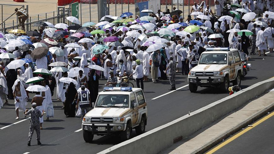 Police vehicles drive past pilgrims on a road in Mina, near the holy city of Mecca September 24, 2015. At least 310 pilgrims were killed on Thursday in a crush at Mina, outside the Muslim holy city of Mecca, where some two million people are performing the annual Haj pilgrimage, Saudi authorities said. REUTERS/Ahmad Masood - RTX1S7WW