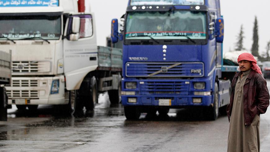 A driver stands next to the trucks lined at the Oncupinar borger crossing on the Turkish-Syrian border in the southeastern city of Kilis January 13, 2012. Since Turkey late last year took the side of anti-government demonstrators seeking the downfall of President Bashar al-Assad, truckers plying the route between the border and the Syrian city of Aleppo have made an easy target for Assad loyalists. Picture taken January 13, 2012. To match feature TURKEY-SYRIA/TRADE  REUTERS/Umit Bektas (TURKEY - Tags: TRANS
