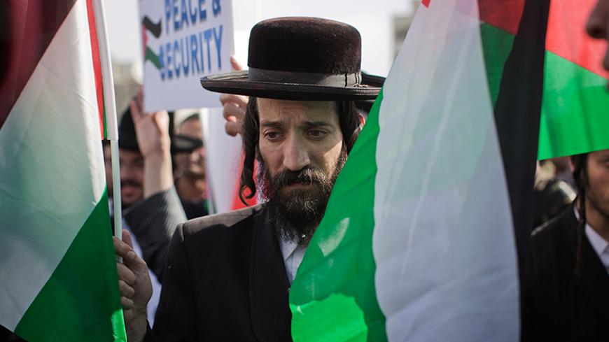A member of Neturei Karta, a fringe ultra-Orthodox Jewish movement within the anti-Zionist bloc, carries Palestinian flags during a rally marking the tenth anniversary of the death of late Palestinian leader Yasser Arafat, in the West Bank city of Ramallah November 11, 2014. Neturei Karta is a small anti-Zionist organization that says it adheres strictly to the Torah, the Jewish holy book, which it says forbids the establishment of a Jewish state before the coming of the Messiah. It supports Palestinian sov