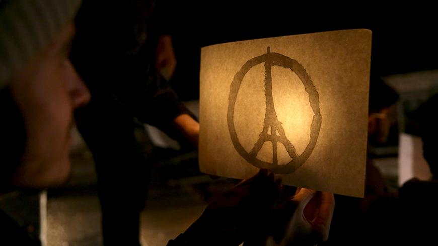A man carries a candle and a placard with an image of the Eiffel tower in tribute to the victims of the Paris attacks in the town of Duma, eastern Ghouta in Damascus November 14, 2015. Picture taken November 14, 2015. REUTERS/Bassam Khabieh - RTS75VU