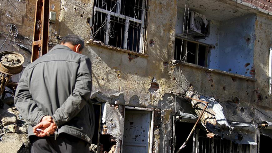 A man stands in front of a building, which was damaged during the security operations and clashes between Turkish security forces and Kurdish militants, in Silvan, in the Kurdish-dominated southeastern Diyarbakir province, Turkey, November 15, 2015. A round-the-clock curfew ended in three districts of the town of Silvan after 12 days on Saturday. REUTERS/Sertac Kayar  - RTS77Z6