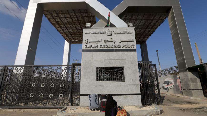 A Palestinian woman sits in front of the gate of Rafah border crossing as she waits for a travel permit to cross into Egypt, in Rafah in the southern Gaza Strip June 14, 2015. Egypt opened the Rafah border crossing on Saturday to allow Palestinians to travel in and out of the Gaza Strip for the first time in three months, in a possible sign of easing tension between Cairo and Gaza's dominant Islamist Hamas movement. Gaza, a small impoverished coastal enclave, is under blockade by neighbouring Israel, and Eg