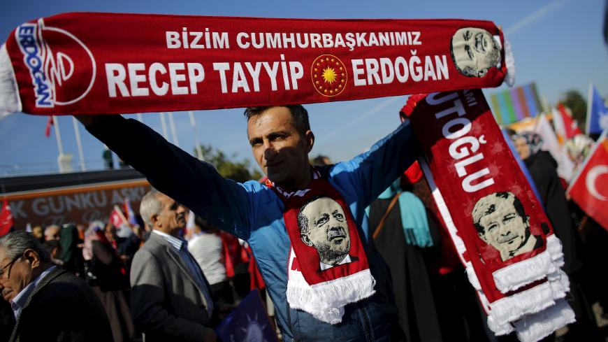 A man holds scarves bearing the names and images of Turkish Prime Minister Ahmet Davutoglu (R) and President Tayyip Erdogan as supporters of the AK Party gather to wait for the arrival of Davutoglu in Istanbul, Turkey November 3, 2015. Erdogan said on Monday the nation had voted for stability in a parliamentary election that saw the AK Party he founded win almost 50 percent of the vote, and said the world should respect the result.  REUTERS/Murad Sezer - RTX1UIYW