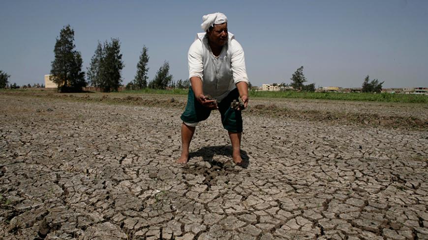 An Egyptian farmer removes pieces of cracked earth from his fields in the village near Balqis, 260 km (162 miles) northeast of  Cairo June 14, 2008. REUTERS/Nasser Nuri   (EGYPT) - RTX6XNE