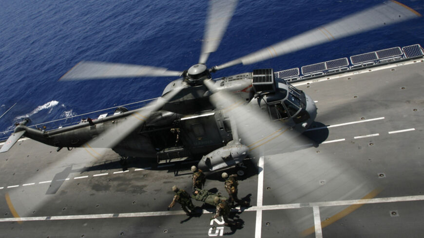 Soldiers maneuver close to an helicopter aboard the Italian aircraft carrier "Giuseppe Garibaldi" during the North Atlantic Treaty Organization (NATO) operation codenamed "Unified Protectors" on June 15, 2011 in the Mediterranean sea.   AFP PHOTO/ MARCELLO PATERNOSTRO (Photo credit should read MARCELLO PATERNOSTRO/AFP/Getty Images)