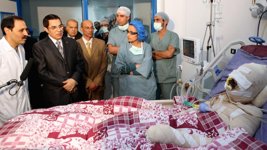A handout picture released by the Tunisian Presidency shows Tunisian president Zine El-Abidine Ben Ali (2nd L)  looking at Mohamed Al Bouazzizi (R), during his visit at the hopital  in Ben Arous near Tunis on December 28, 2010.  Mohamed Al Bouazzizi, a 26-year-old university graduate, who was forced to sell fruit and vegetables on the streets, doused himself in petrol and set himself alight on December 17, which left him in a serious condition with severe burns.  Days of rioting in Tunisia by mostly jobless