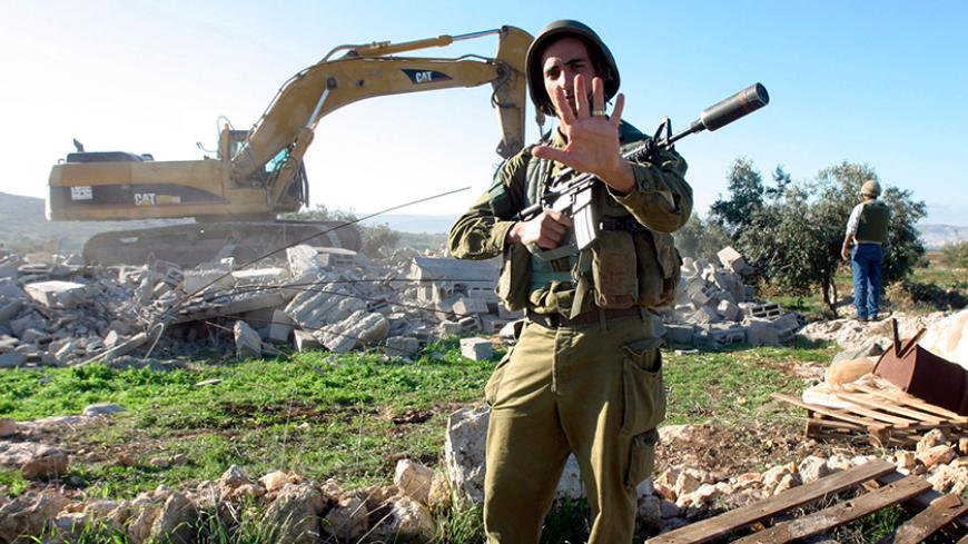 An Israeli soldier gestures as a bulldozer demolishes two Palestinian houses in the West Bank village of Arabuna near Jenin November 28, 2006.  According to the Israeli authorities, the houses were demolished due to lack of permits.    
REUTERS/Mohamad Torokman   (WEST BANK) - RTR1JRSA