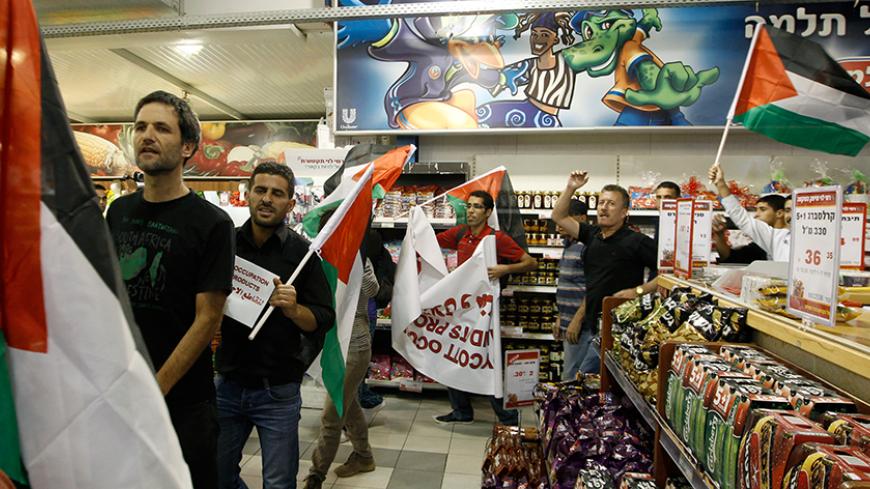 Foreign and Palestinian activists hold Palestinian flags as they march through a supermarket in the West Bank Jewish settlement of Modiin Illit October 24, 2012. Some 50 activists marched through the supermarket and tried to block a road in the settlement on Wednesday during a protest against Jewish settlements and in a call to boycott settlement products. REUTERS/Ammar Awad (WEST BANK - Tags: POLITICS CIVIL UNREST FOOD TPX IMAGES OF THE DAY) - RTR39IM8