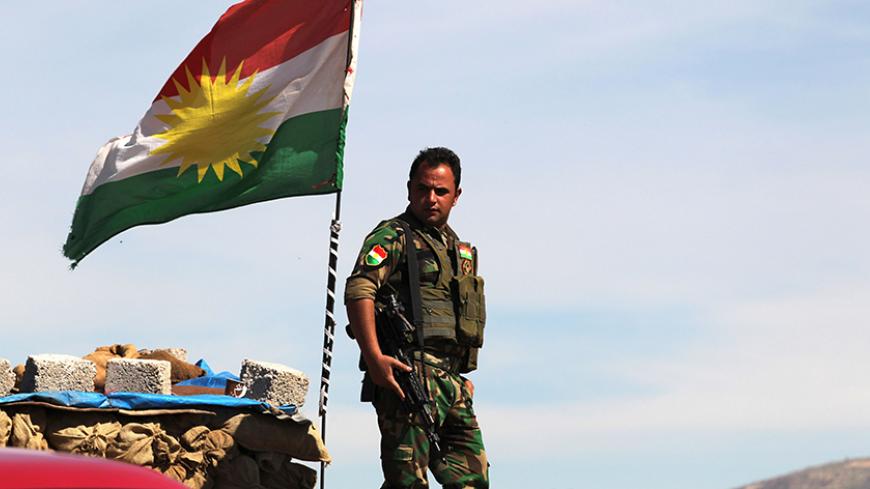 A Kurdish flag is seen as a member of the Kurdish Peshmerga forces stands guard at a security point on Bashiqa mountain, overlooking Islamic State held territories of Mosul, 12 km northeast of Mosul City, March 7, 2015.  REUTERS/Asmaa Waguih (IRAQ - Tags: POLITICS MILITARY CONFLICT TPX IMAGES OF THE DAY) - RTR4SF4S