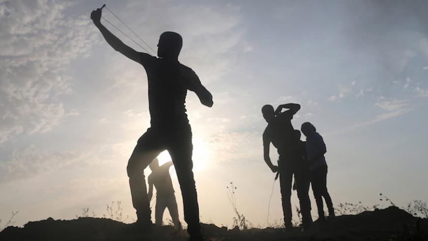 A Palestinian protester uses a slingshot to hurl stones towards Israeli troops during clashes near the border between Israel and Central Gaza Strip October 20, 2015. A three-week-old uprising by knife-wielding, Internet-generation teenagers against Israelis has left 80-year-old Palestinian President Mahmoud Abbas looking like yesterday's man, unable either to oppose the violence or openly endorse it. REUTERS/Ibraheem Abu Mustafa - RTS5APW