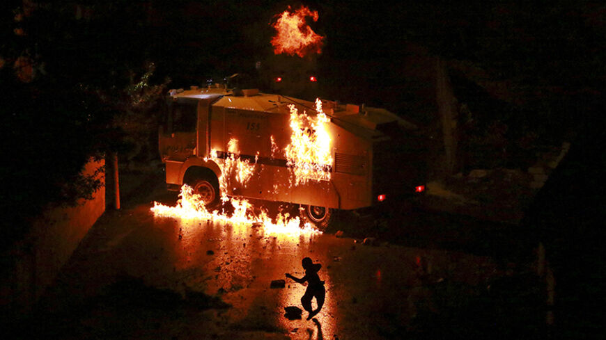 A man runs a way from a burning police vehicle during clashes between riot police and Kurdish militants in Van, eastern Turkey, August 27, 2015. Seven people, including at least four civilians, were killed on Thursday in clashes between Turkey's armed forces and militants in the mainly Kurdish southeast, security sources and the army said. A 2-1/2-year-old ceasefire between Turkey and Kurdish militants collapsed in July after a group close to Kurdistan Workers Party (PKK) rebels shot dead two police officer