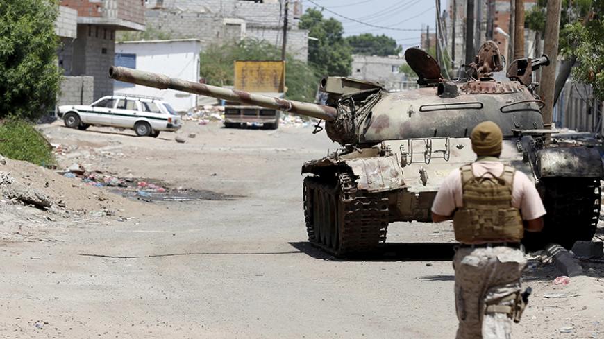 A soldier from the Saudi-led coalition walks past a broken-down tank on a street in Yemen's southern port city of Aden September 27, 2015. As Gulf-backed forces assemble in Marib province east of Sanaa ahead of a widely expected thrust towards the Houthi-held capital, the fate of Aden and its hinterland may offer a glimpse at whether some form of central government can be resurrected. To match Insight YEMEN-SECURITY/ADEN   REUTERS/Faisal Al Nasser - RTX1SQ8T
